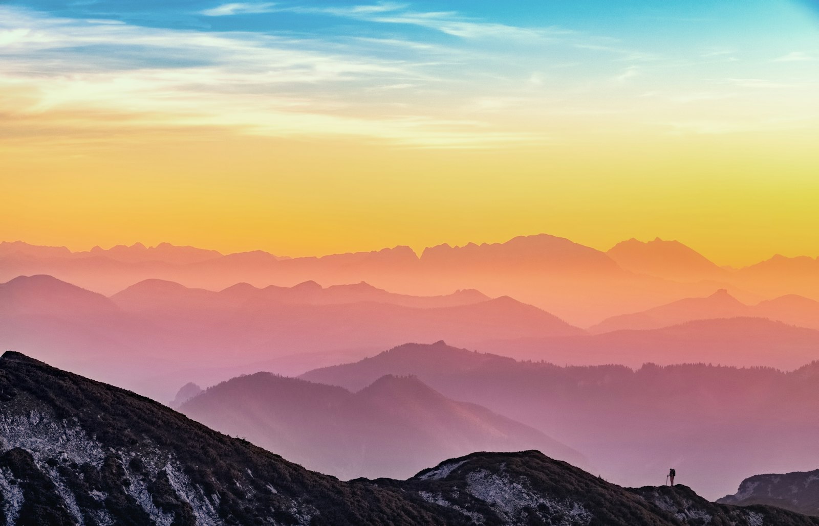 Silueta de una persona contemplando el atardecer desde una cima