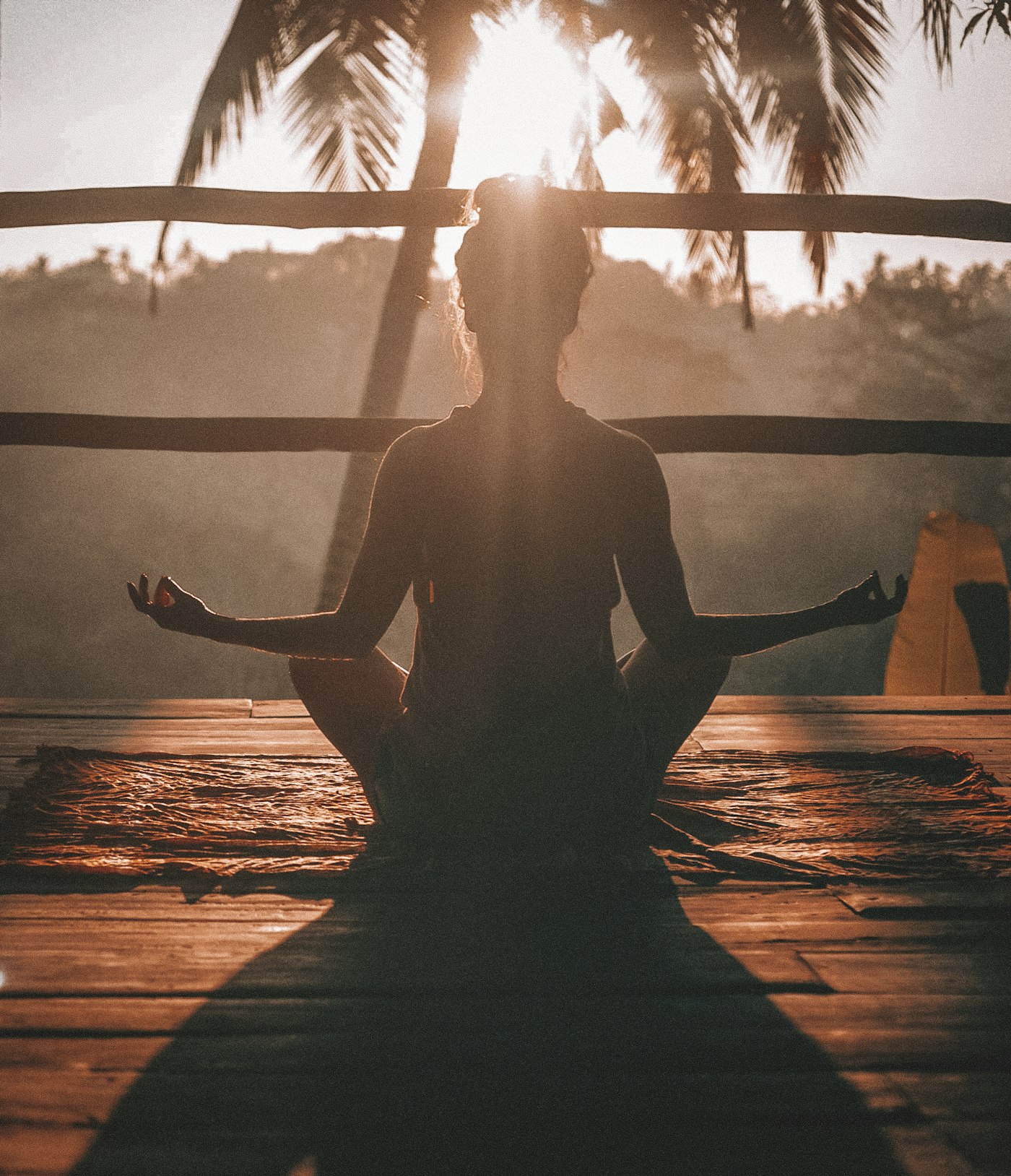 Silueta en meditación sobre una plataforma de madera al atardecer
